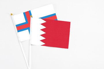 Bahrain and Faroe Islands stick flags on white background. High quality fabric, miniature national flag. Peaceful global concept.White floor for copy space.