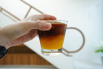 Hand holding a cup of iced orange espresso coffee