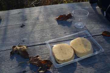 cheese among yellow leaves on a wooden table