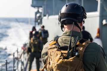 Military soldiers boarding group control and search for refugees on ship deck during operation on...