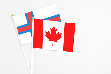 Canada and Faroe Islands stick flags on white background. High quality fabric, miniature national flag. Peaceful global concept.White floor for copy space.