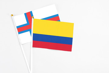 Colombia and Faroe Islands stick flags on white background. High quality fabric, miniature national flag. Peaceful global concept.White floor for copy space.