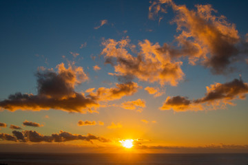 Dramatic cloudy golden blue sunset or sunrise over the ocean.