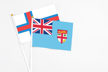 Fiji and Faroe Islands stick flags on white background. High quality fabric, miniature national flag. Peaceful global concept.White floor for copy space.