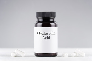 nutritional supplement hyaluronic acid bottle and capsules on gray