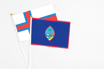 Guam and Faroe Islands stick flags on white background. High quality fabric, miniature national flag. Peaceful global concept.White floor for copy space.