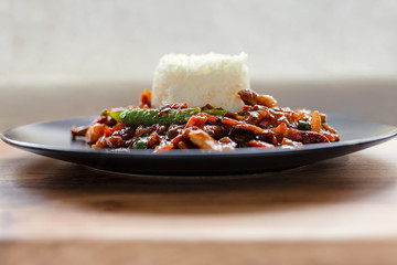 Stir fry vegetables and rice, served on a black plate on a wooden table