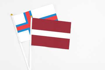 Latvia and Faroe Islands stick flags on white background. High quality fabric, miniature national flag. Peaceful global concept.White floor for copy space.