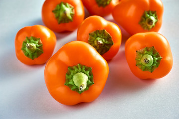 Small bell peppers. Many orange mini peppers on a light blue background with copy space.