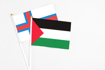 Palestine and Faroe Islands stick flags on white background. High quality fabric, miniature national flag. Peaceful global concept.White floor for copy space.