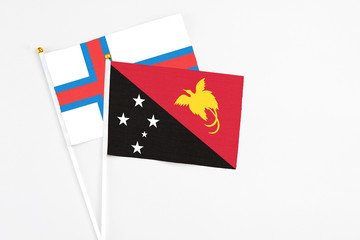 Papua New Guinea and Faroe Islands stick flags on white background. High quality fabric, miniature national flag. Peaceful global concept.White floor for copy space.