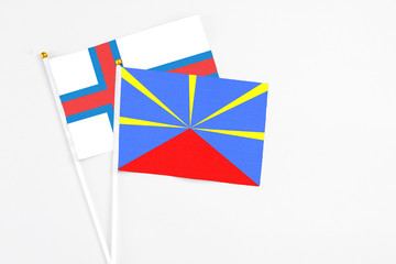 Reunion and Faroe Islands stick flags on white background. High quality fabric, miniature national flag. Peaceful global concept.White floor for copy space.