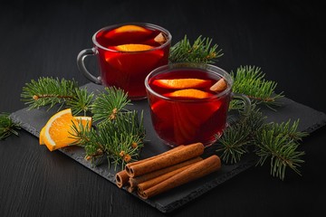  Christmas mulled red wine with spices and fruits on a wooden black rustic table. Traditional hot drink at Christmas time