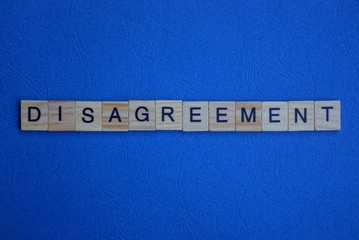 the word disagreement of brown wooden letters lies on a blue table