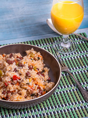 Traditional Jamaican dish - rice with beans and vegetables in a bowl and a glass of juice on a bamboo napkin, delicious vegetarian dish