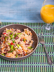 Traditional Mexican dish - rice with beans and vegetables with chili peppers and green onions in a bowl and a glass of juice on a bamboo napkin, tasty and healthy vegetarian dish