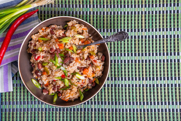 Traditional Jamaican and Mexican dish - rice with beans and vegetables and hot pepper in a bowl on a bamboo napkin, top view, copy space