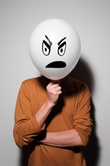 A man holding white balloon with an evil emotion instead of head. Negative Thinking concepts.