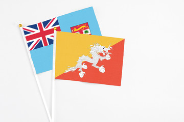 Bhutan and Fiji stick flags on white background. High quality fabric, miniature national flag. Peaceful global concept.White floor for copy space.