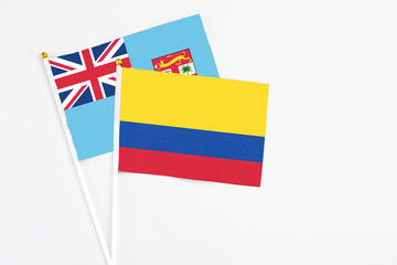 Colombia and Fiji stick flags on white background. High quality fabric, miniature national flag. Peaceful global concept.White floor for copy space.