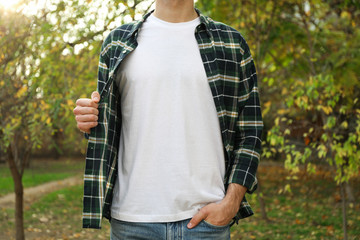 Men in white t-shirt and checkered shirt in park, copy space