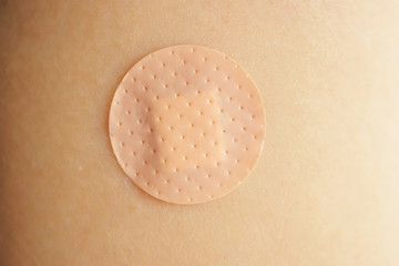 Close up circle brown adhesive bandage on patient arm after medicine injection or vaccination