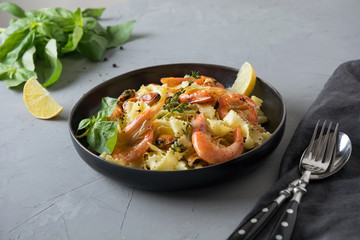 Pasta reginelle with seafood, shrimps, mussels on gray stone table, close up. Traditional dish in Italian restaurant.