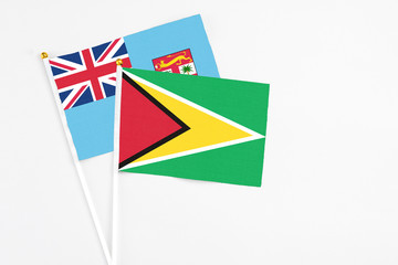 Guyana and Fiji stick flags on white background. High quality fabric, miniature national flag. Peaceful global concept.White floor for copy space.