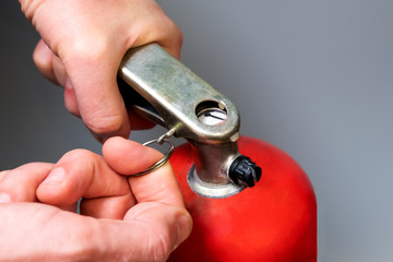Male finger pulls out a pin. A man pulls out a safety ring from a red fire extinguisher. Close-up....