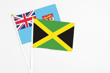 Jamaica and Fiji stick flags on white background. High quality fabric, miniature national flag. Peaceful global concept.White floor for copy space.