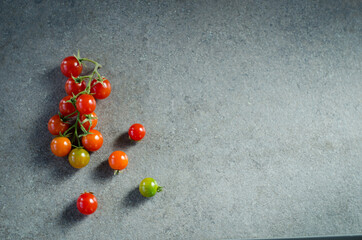 Cherry tomatoes on the vine on black stone background. Concept for healthy nutrition. Symbolic image. Copy space.