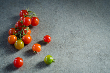 Cherry tomatoes on the vine on black stone background. Concept for healthy nutrition. Symbolic image. Copy space.