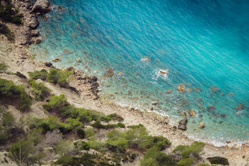 ibizTop view of a rocky beach from the top birds view turquoise sea water green plants vegetation Mediterranean beach on Ibiza island near Cala D'Hort a
