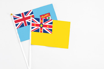 Niue and Fiji stick flags on white background. High quality fabric, miniature national flag. Peaceful global concept.White floor for copy space.