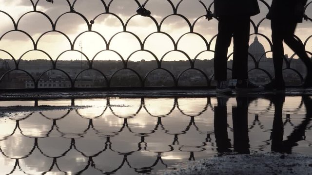 roma, belvedere del pincio, pozzanghera che riflette skyline della citt&agrave;, ragazzi in silhouette che si fanno un selfie fotografa
