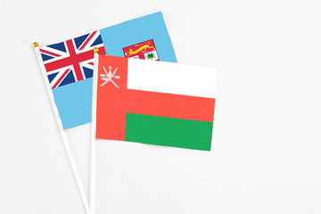Oman and Fiji stick flags on white background. High quality fabric, miniature national flag. Peaceful global concept.White floor for copy space.
