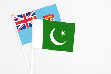 Pakistan and Fiji stick flags on white background. High quality fabric, miniature national flag. Peaceful global concept.White floor for copy space.