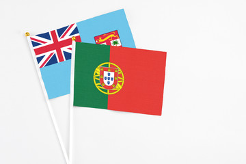 Fototapeta premium Portugal and Fiji stick flags on white background. High quality fabric, miniature national flag. Peaceful global concept.White floor for copy space.