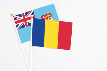 Romania and Fiji stick flags on white background. High quality fabric, miniature national flag. Peaceful global concept.White floor for copy space.
