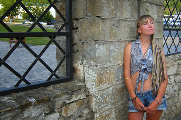 Sexy beautiful woman stands on a summer day near a stone fence