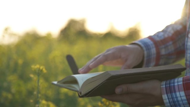 The farmer looks at a notebook on the field
