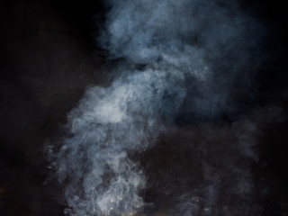 Light puffs of smoke from a fire on a dark background. Studio photography