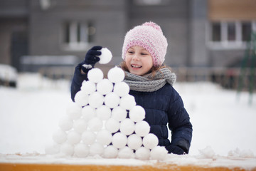 Portrait of cute little kid girl playing with snowballs outdoors, walking and having fun on a...