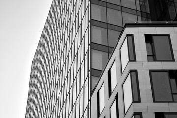 Curtain wall made of toned glass and steel constructions under sky. A fragment of a building. Black and white.