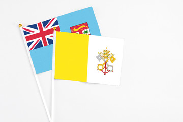 Vatican City and Fiji stick flags on white background. High quality fabric, miniature national flag. Peaceful global concept.White floor for copy space.