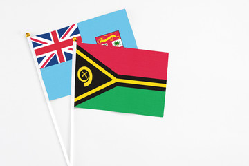 Vanuatu and Fiji stick flags on white background. High quality fabric, miniature national flag. Peaceful global concept.White floor for copy space.