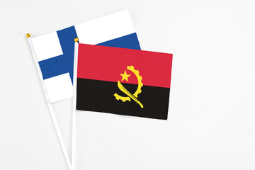 Angola and Finland stick flags on white background. High quality fabric, miniature national flag. Peaceful global concept.White floor for copy space.