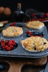 streusel muffins with blueberry, raspberry and red currant on rustic wooden table