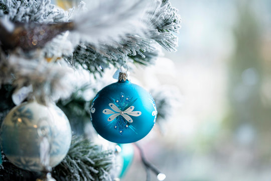 Christmas background. Detail view of blue and silver baubles and festive decorations hanging on a white christmas tree.