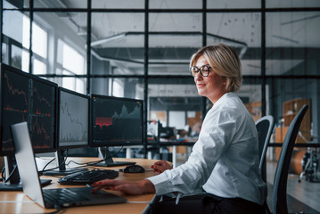 Female stockbroker in formal clothes works in the office with financial market